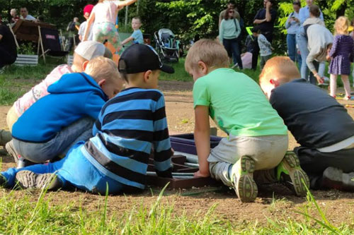 Dzieci w parku. Zabawa przy torze kapslowym.